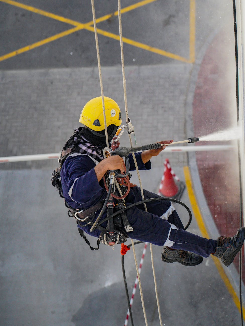 person in yellow helmet using a power spray